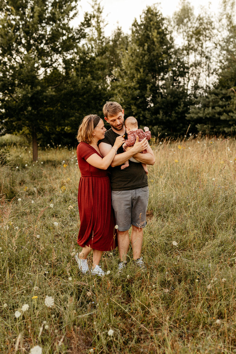 Mann und Frau mit ihrem Baby auf dem Arm auf einer Wiese